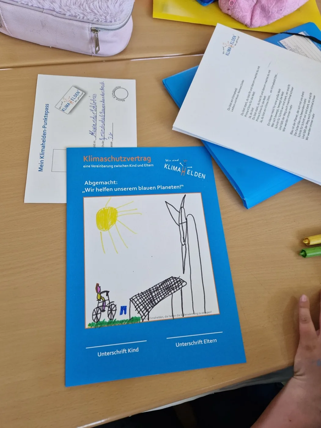 Ein ausgefüllter Klimahelden-Punktepass neben dem Klimaschutz-Vertrag