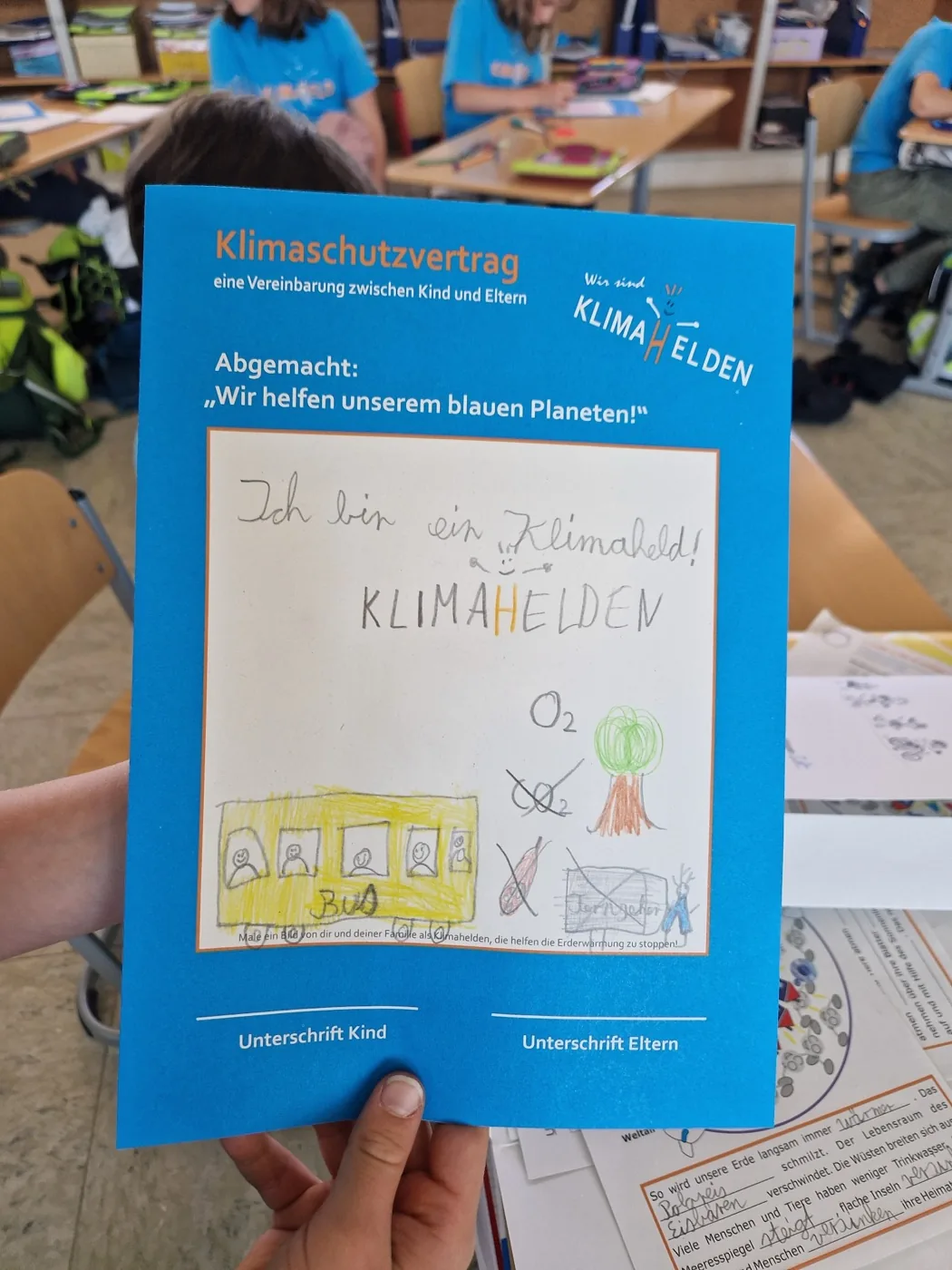 Ein Kind hält seinen gemalten Klimaschutz-Vertrag hoch